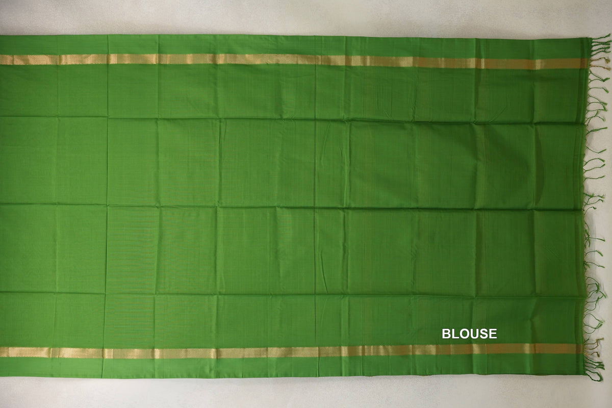 Leaf green Maheshwari silk cotton blouse piece laid flat, with narrow gold-patterned bands along the top and bottom and green tassels at one end.