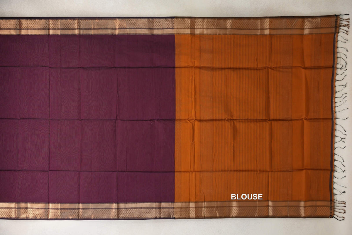 Maheshwari silk cotton saree laid flat, with a deep plum body, deep orange blouse piece, patterned metallic-toned borders and tassels at one end.