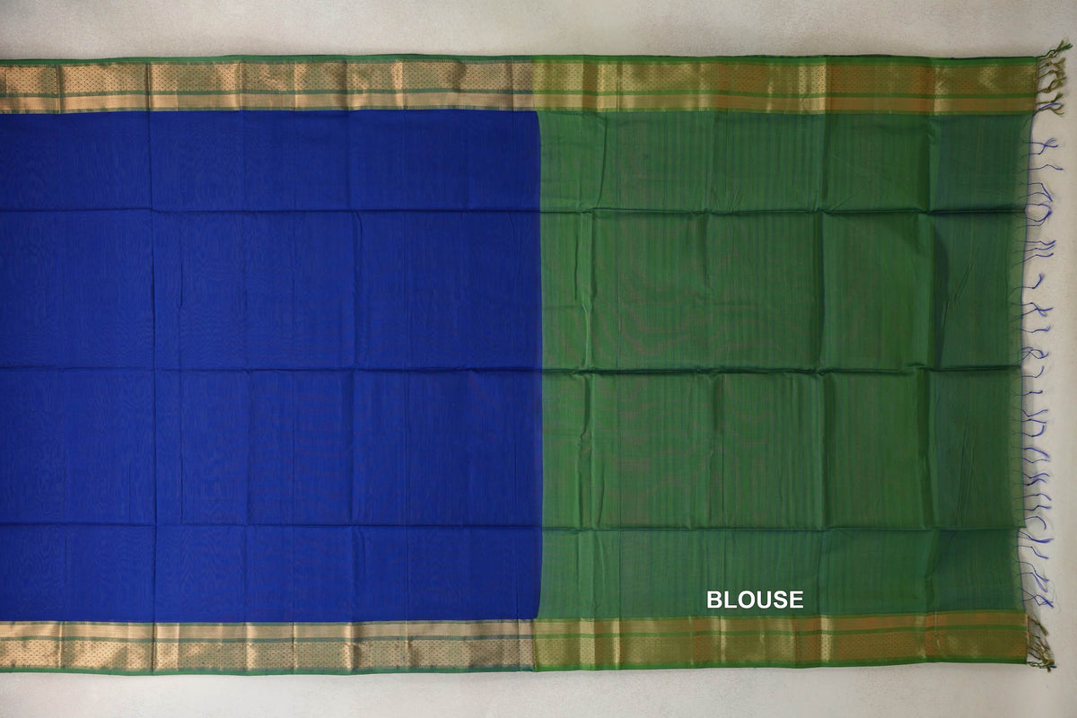 Maheshwari silk cotton saree laid flat, with a bright royal blue body beside a leaf green blouse piece, metallic-looking borders and loose fringe.