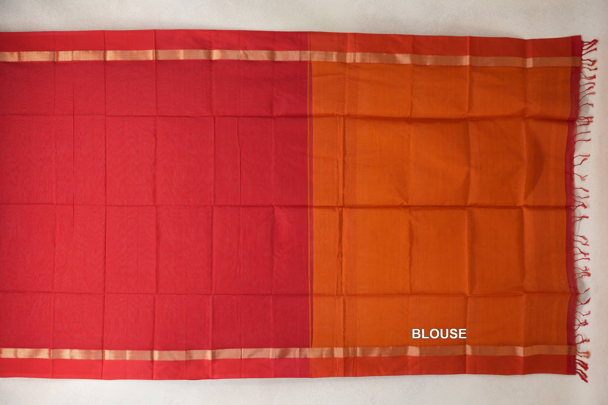 Vermilion red Maheshwari silk cotton saree laid flat beside its deep orange blouse piece, with gold-toned woven borders and tassels.