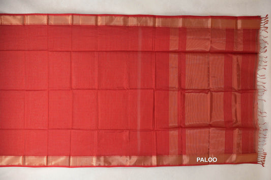 Tomato red Maheshwari silk cotton saree laid flat, with a fine checked body, gold zari borders and a striped pallu with red tassels.