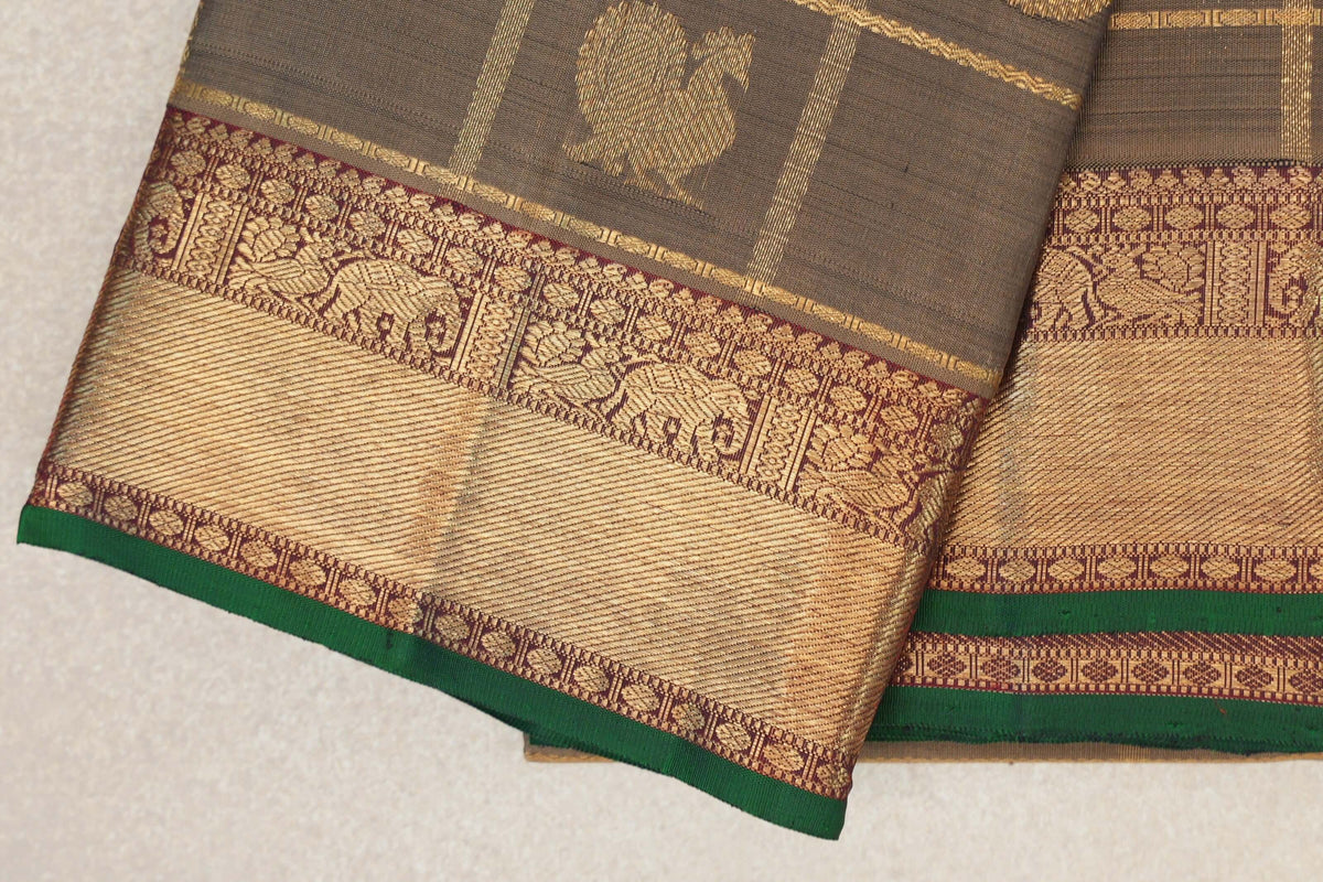 Folded olive green Kanjivaram silk saree showing a deep maroon and gold elephant-patterned border with bottle green selvedge.