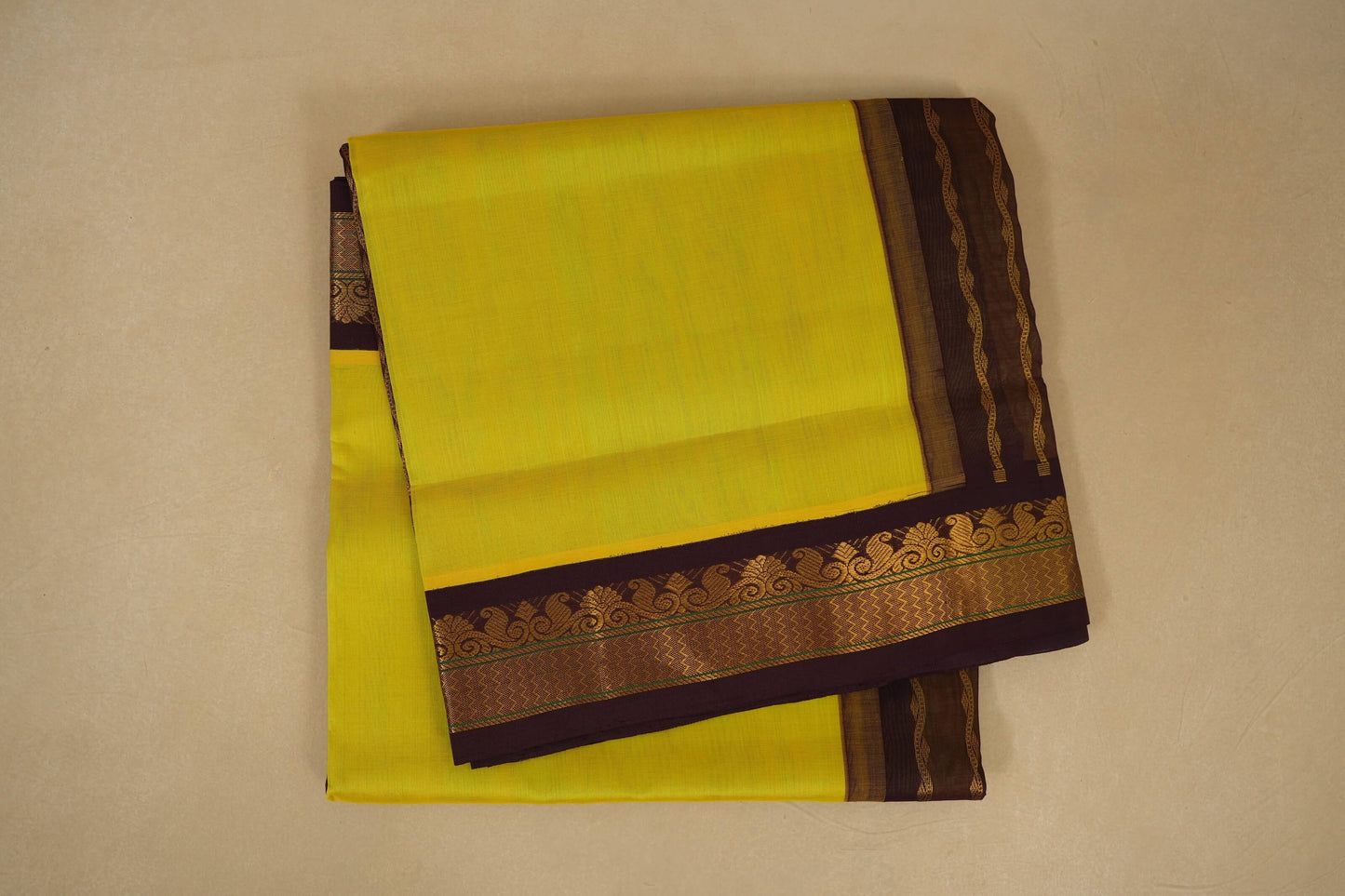 Yellow saree with a brown border on a beige background , silk cotton , nine and a half yards saree folded