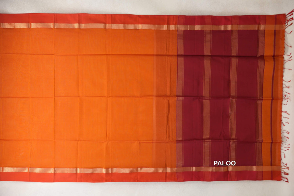 Spread-out Maheshwari silk cotton saree with a plain reddish orange body, orangish red borders, and a striped reddish maroon pallu with tassels.