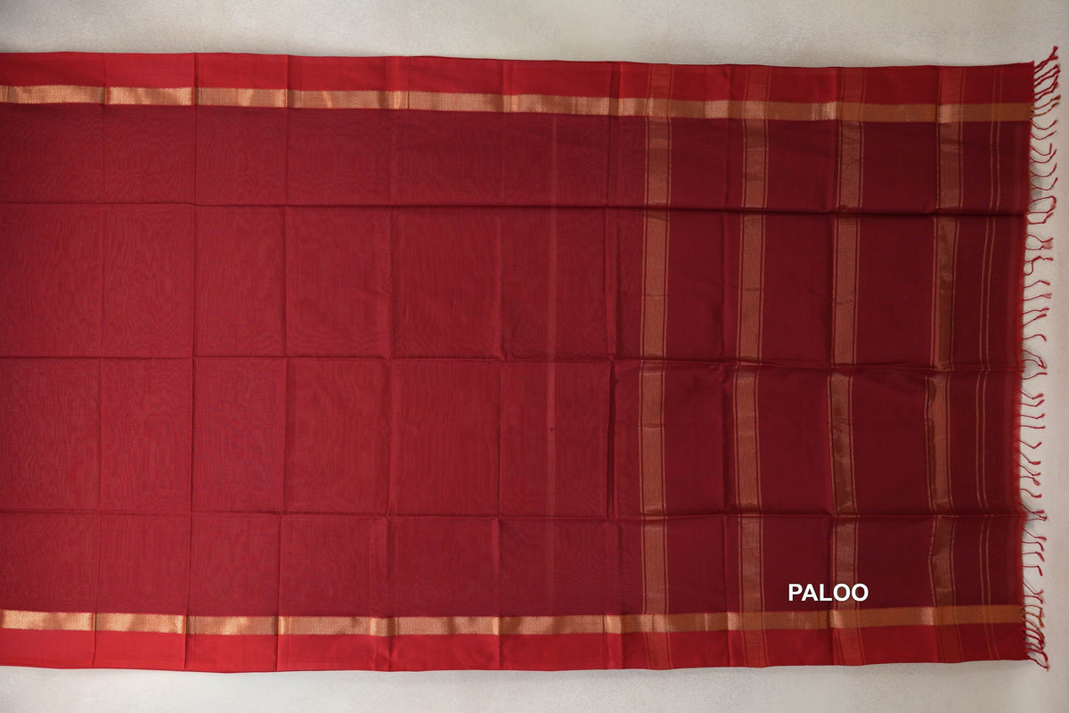 Deep red Maheshwari silk cotton saree pallu laid flat, with gold-toned stripes, matching borders and tassels along the end.