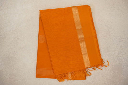 Folded mango yellow Maheshwari silk cotton saree with a fine checked texture, a shimmering zigzag border and tassels at one end.
