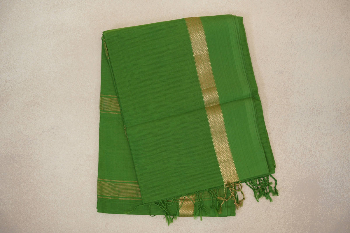 Folded leaf green Maheshwari silk cotton saree with a fine woven texture, gold zigzag border, narrow gold stripes and green tassels.