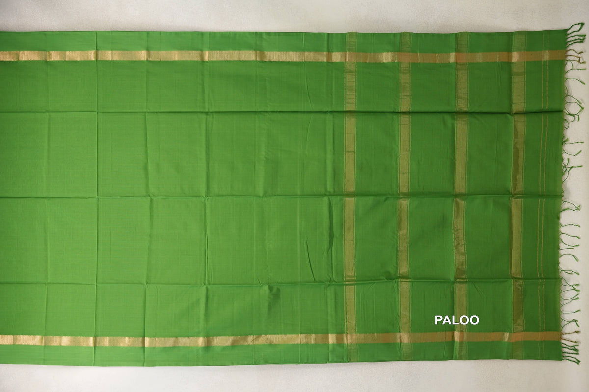 Leaf green Maheshwari silk cotton saree laid flat, showing a plain body, gold-toned borders and a striped pallu with green tassels.