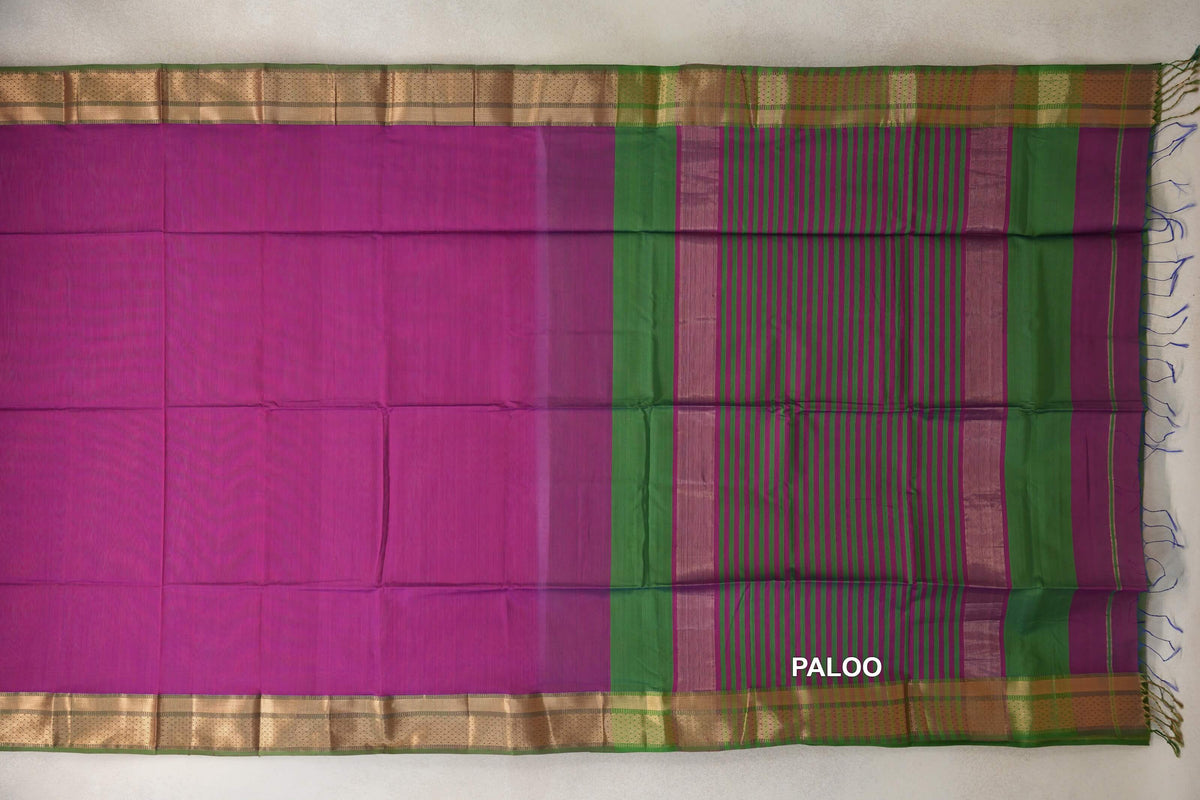 Maheshwari silk cotton saree spread flat, with a plain dark magenta body, leaf green and gold-toned borders, and a striped pallu with tassels.