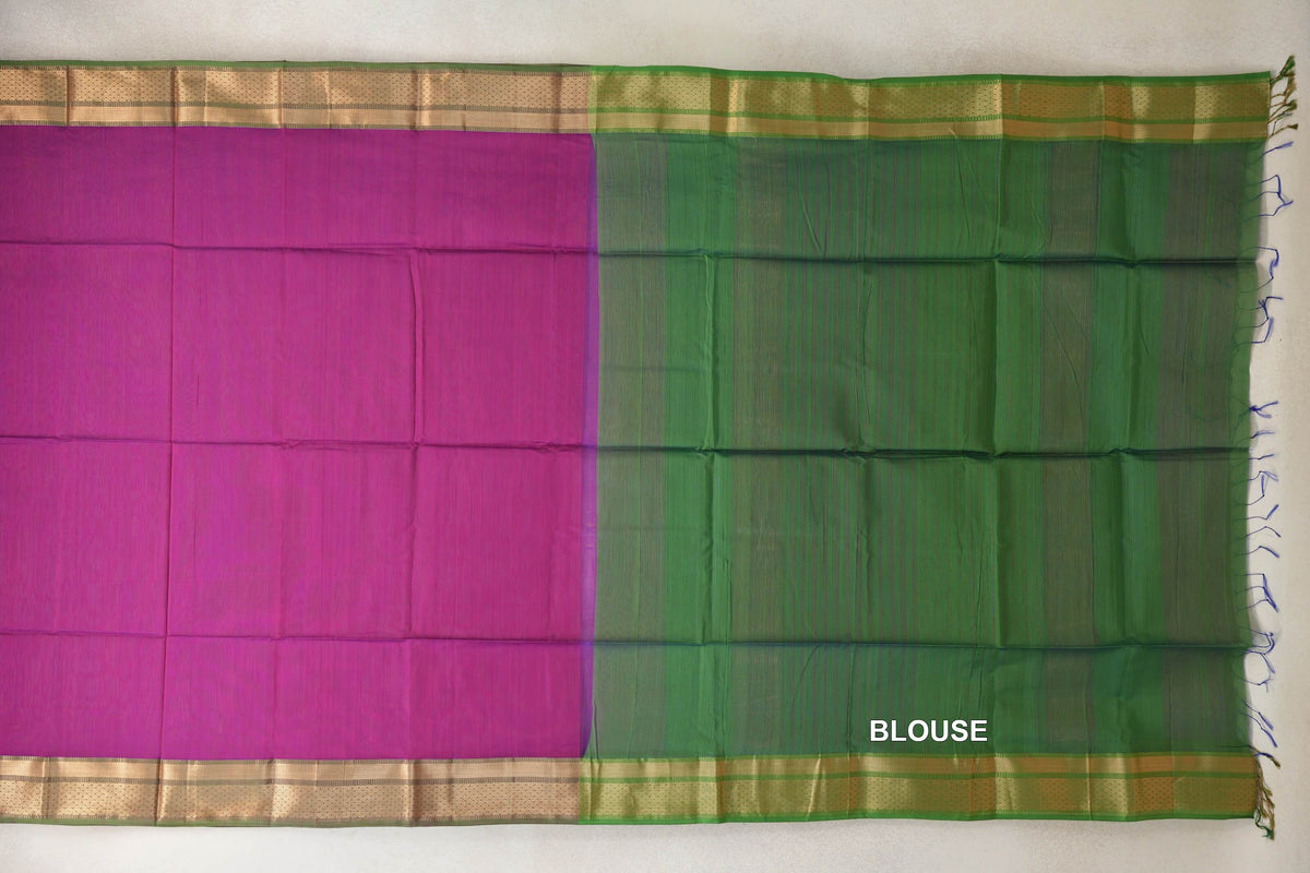 Maheshwari silk cotton saree laid flat, with a dark magenta body, leaf green blouse piece, gold-toned borders and fringe at one end.