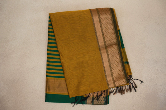 Folded Maheshwari silk cotton saree with a mustard yellow body, patterned gold-toned border and deep emerald green and mustard striped pallu.