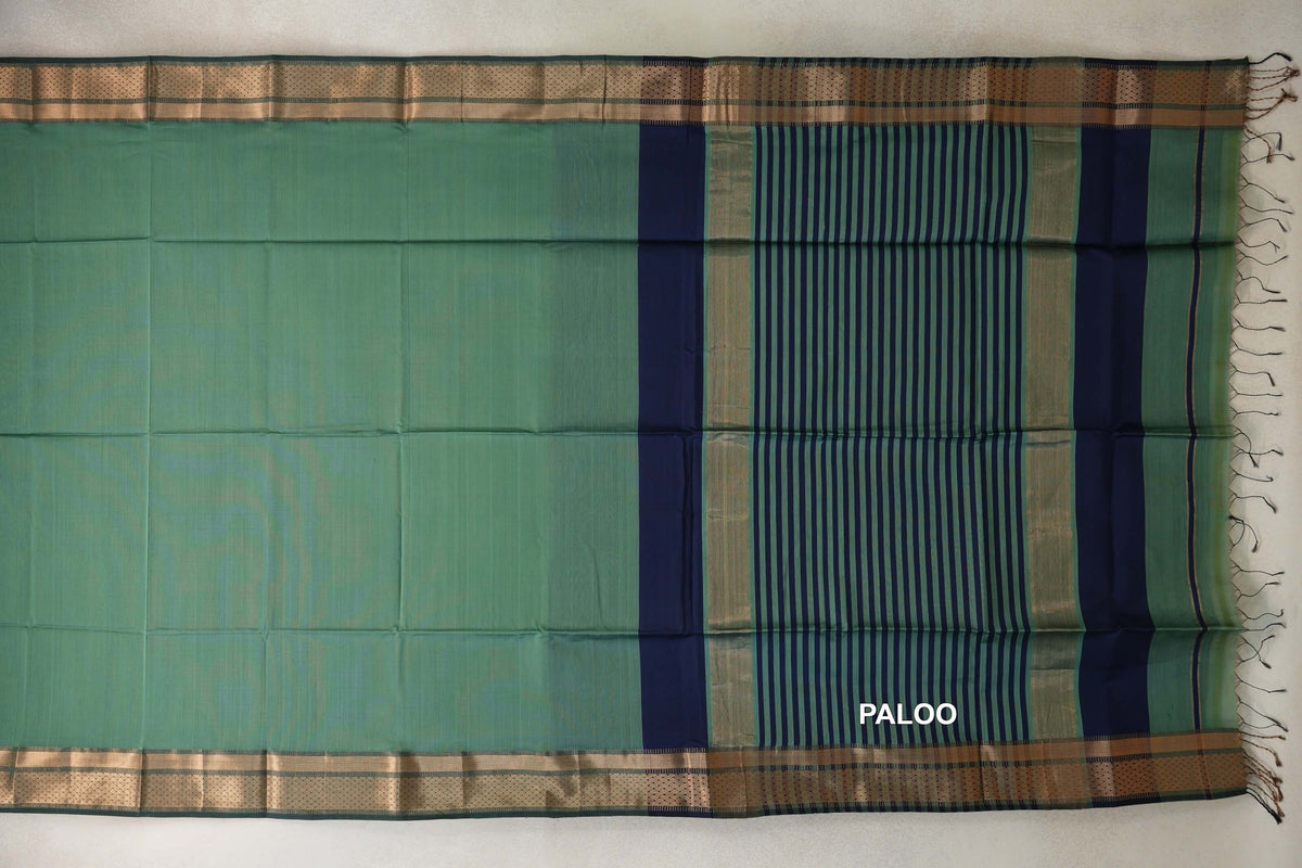 Maheshwari silk cotton saree laid flat, with a plain sea green body, patterned borders and a sea green pallu with navy blue stripes and tassels.