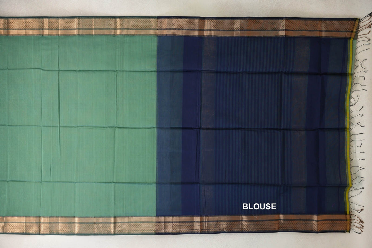 Maheshwari silk cotton saree laid flat, showing a plain sea green body, gold-toned patterned borders and a striped navy blue blouse piece with tassels.