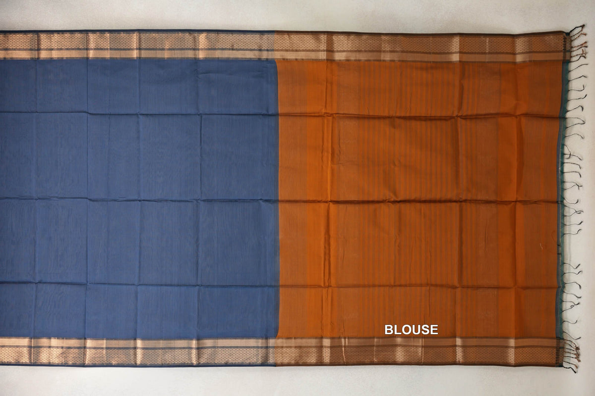 Maheshwari silk cotton saree laid flat, showing a dark grey blue body beside a deep orange blouse piece, patterned borders and tassels.
