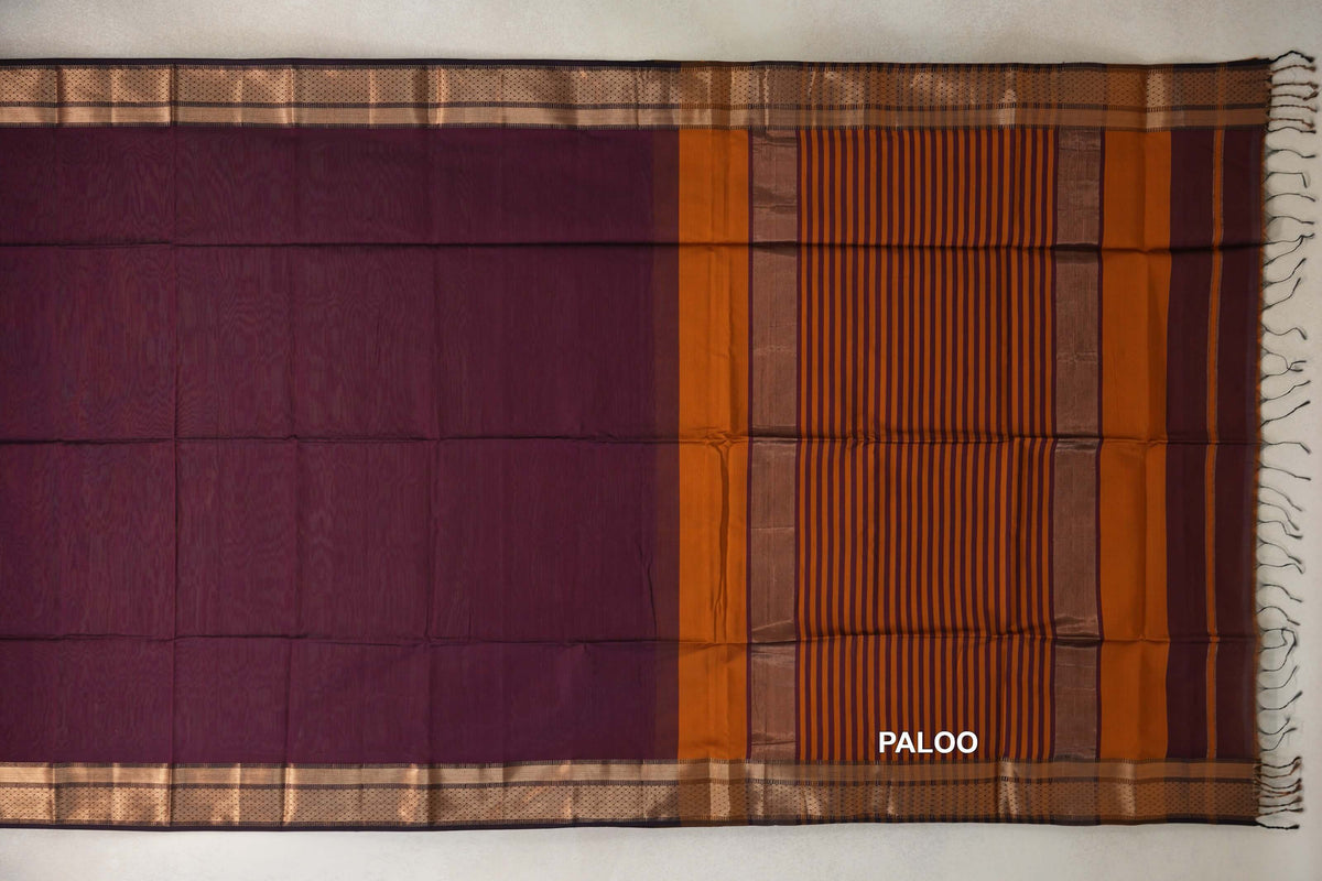 Maheshwari silk cotton saree laid flat, showing a deep plum body, deep orange and plum striped pallu, patterned borders and fringed end.