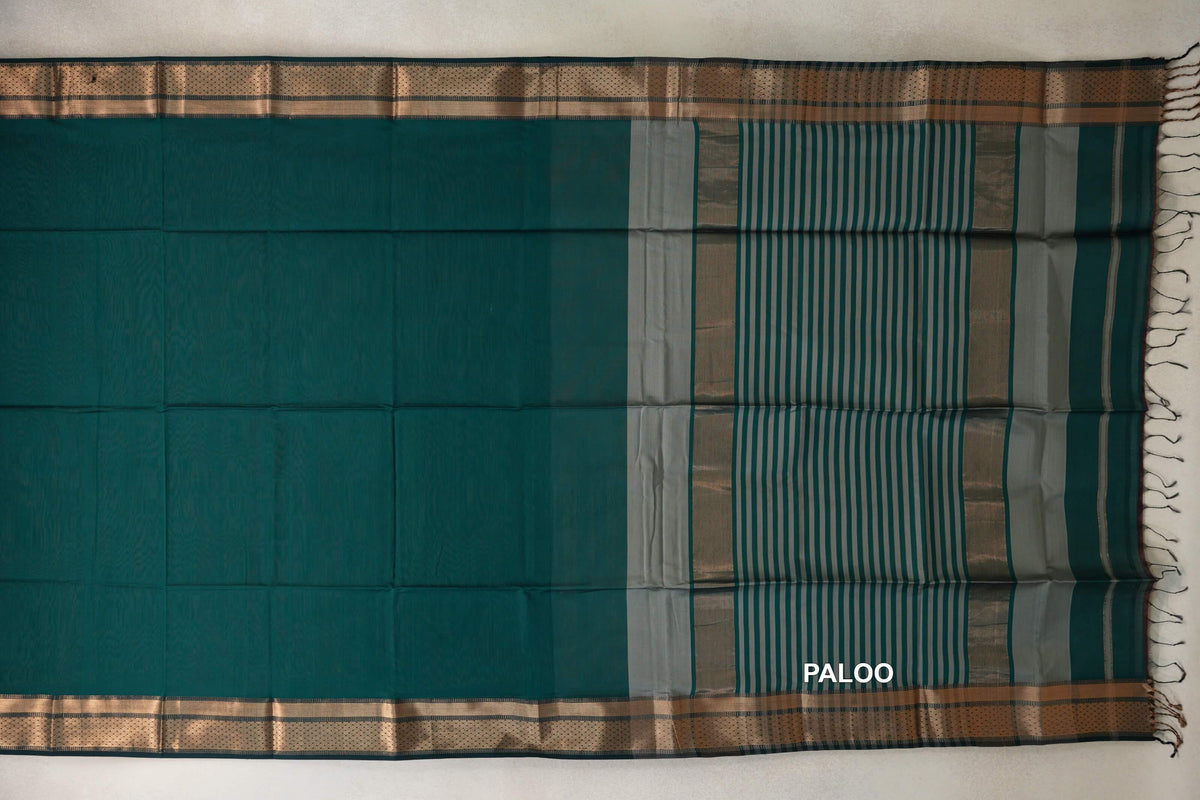 Maheshwari silk cotton saree laid flat, showing a plain peacock green body, patterned borders and a silver grey striped pallu with tassels.