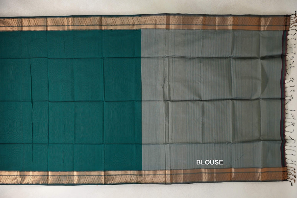 Maheshwari silk cotton saree laid flat, showing a peacock green body, silver grey blouse piece, patterned borders and tassels along the right edge.