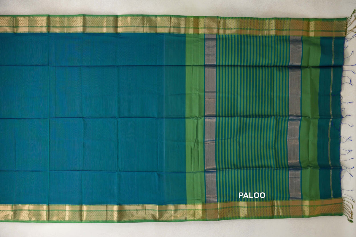 Maheshwari silk cotton saree spread flat, showing a peacock green body, leaf green borders with gold-toned detailing, and a striped blue and green pallu.