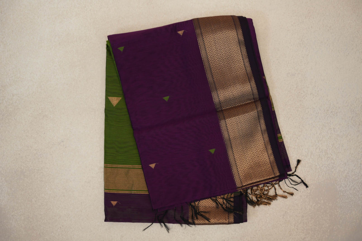 Folded deep purple Maheshwari silk cotton saree with small triangle motifs, a gold-toned chevron border, an olive green section and tassels.