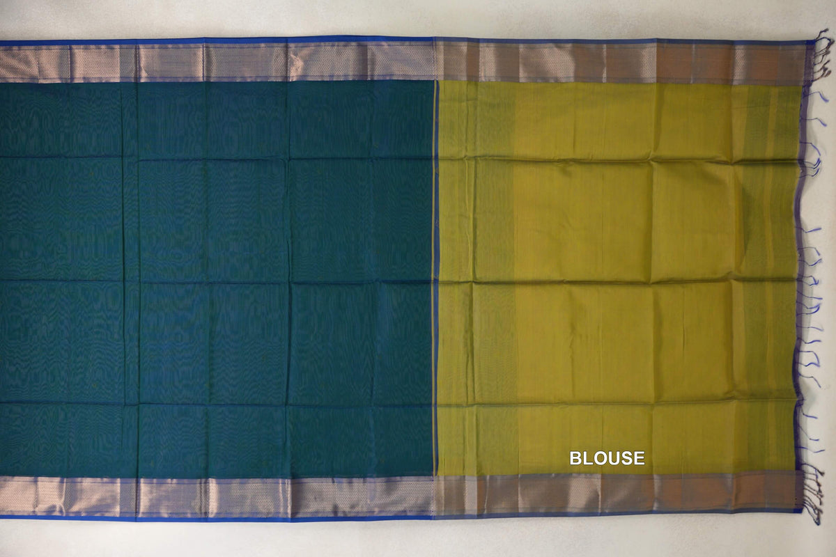 Maheshwari silk cotton saree laid flat, with a peacock green body, royal blue striped borders and a mehandi green blouse piece on the right.