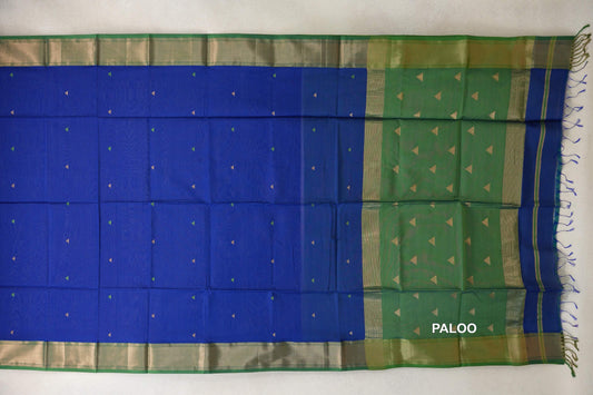 Maheshwari silk cotton saree spread flat, with a royal blue body dotted with small triangles, a leaf green pallu, patterned borders and tassels.