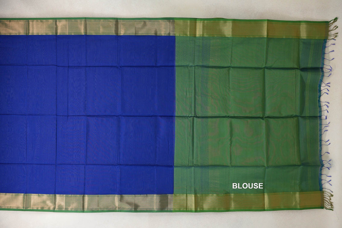 Maheshwari silk cotton saree laid flat, showing a royal blue body, leaf green blouse section, patterned gold-toned borders and tassels.