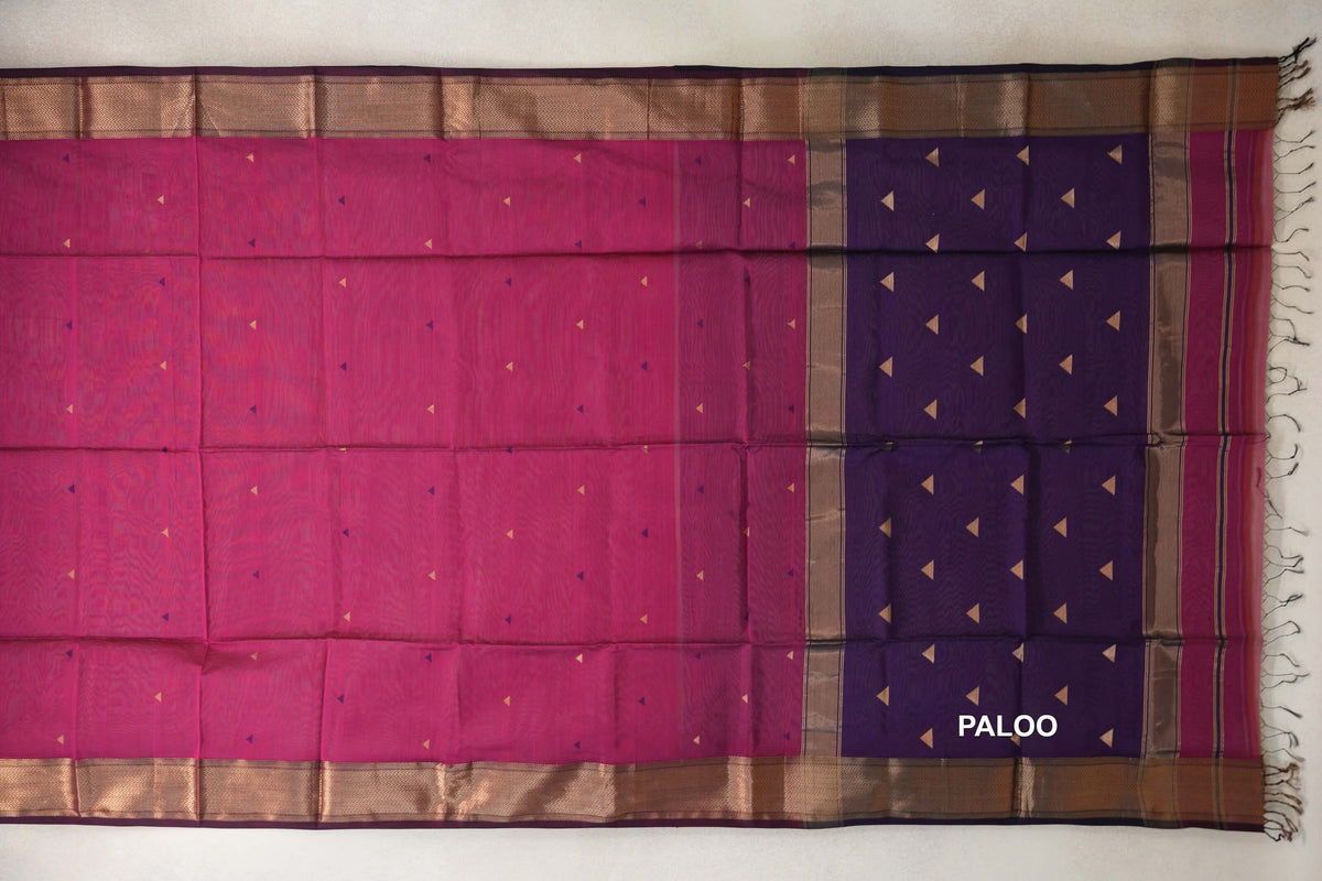 Maheshwari silk cotton saree laid flat, with a deep rani pink body, deep purple pallu, scattered triangles, patterned borders and tassels.
