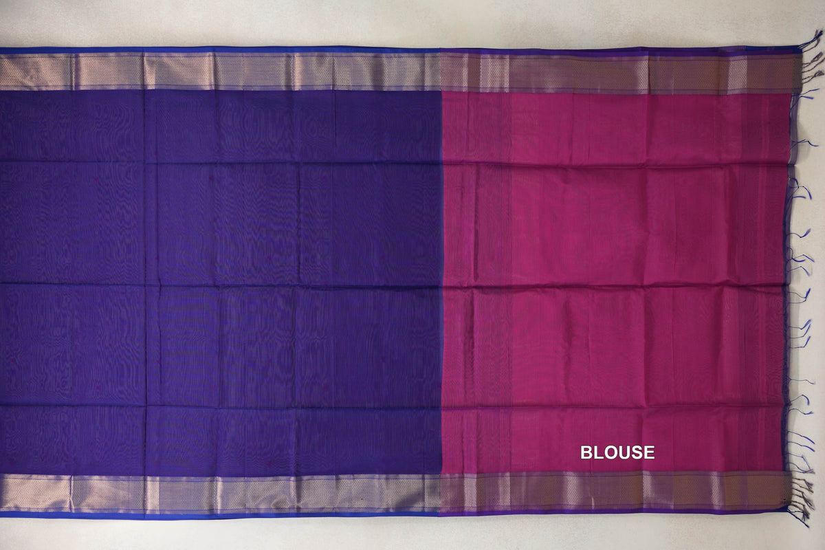 Deep violet Maheshwari silk cotton saree laid flat beside its deep rani pink blouse piece, with zigzag-patterned borders and tassels.