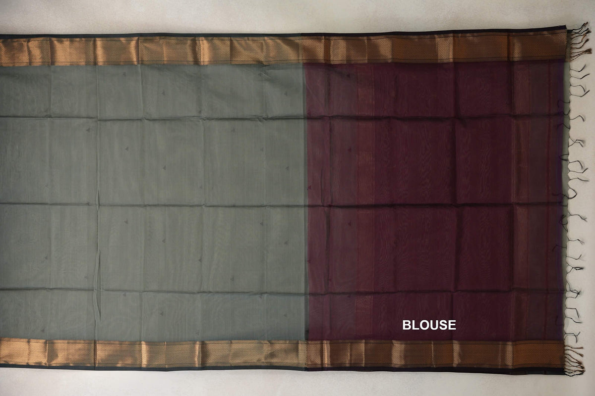 Maheshwari silk cotton saree laid flat, showing a sage green body and deep wine maroon blouse piece, with patterned borders and tassels.