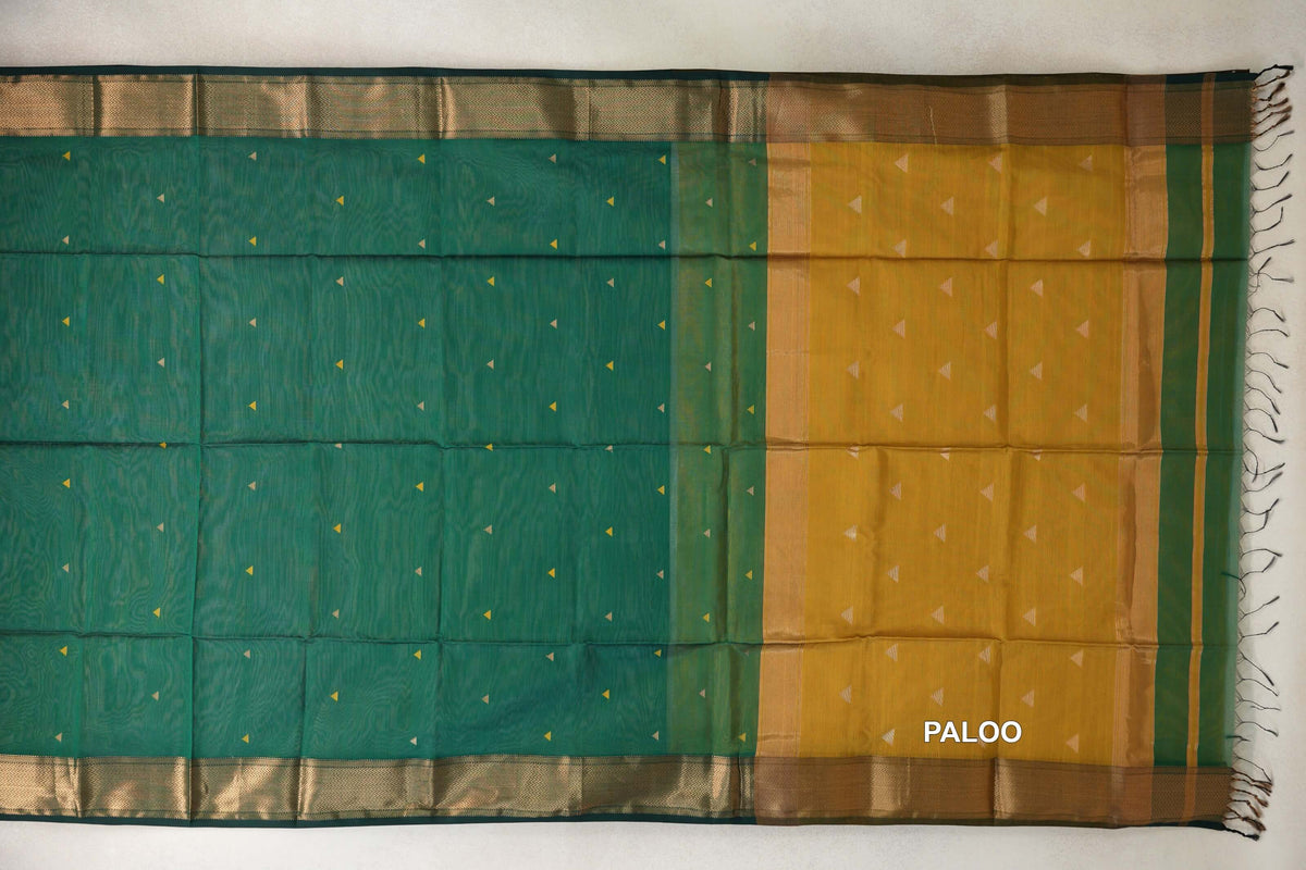 Maheshwari silk cotton saree spread flat, with a bottle green body dotted with small triangles, a mustard yellow pallu, zigzag borders and tassels.