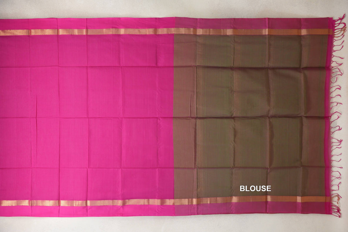 Maheshwari silk cotton saree laid flat, showing a rani pink body beside an olive green blouse section, with gold-toned border stripes and pink tassels.