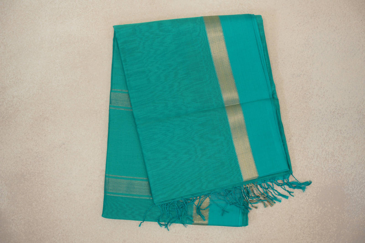 Folded bright aqua green Maheshwari silk cotton saree with a gold-toned woven border, fine stripes and a fringed end.
