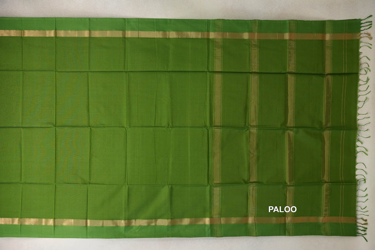 Leaf green Maheshwari silk cotton saree spread flat, with gold-toned borders and a striped pallu ending in green tassels.
