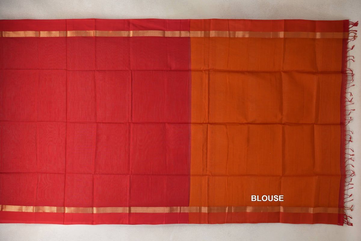 Laid-flat Maheshwari silk cotton saree with a vermilion red body, deep orange blouse piece, narrow gold-toned border stripes and tassels at the right edge.