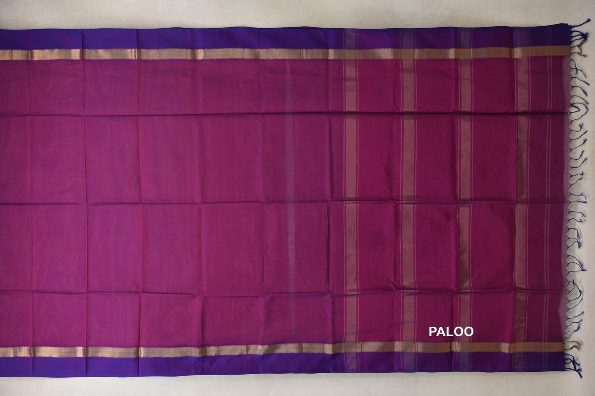 Maheshwari silk cotton saree spread flat, showing a deep magenta body, a striped pallu, violet purple borders and tassels at the end.