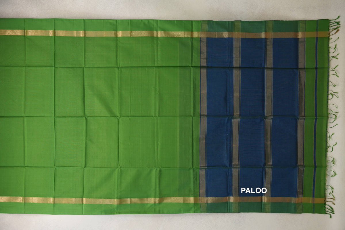 Bright leaf green Maheshwari silk cotton saree spread flat, with gold-toned borders and a peacock blue striped pallu with green tassels.
