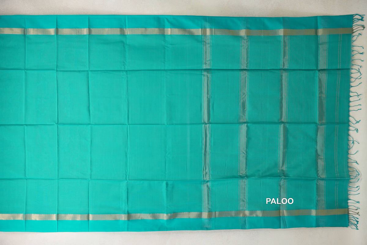 Bright aqua green Maheshwari silk cotton saree laid flat, with silver-toned borders and a striped pallu ending in tassels.