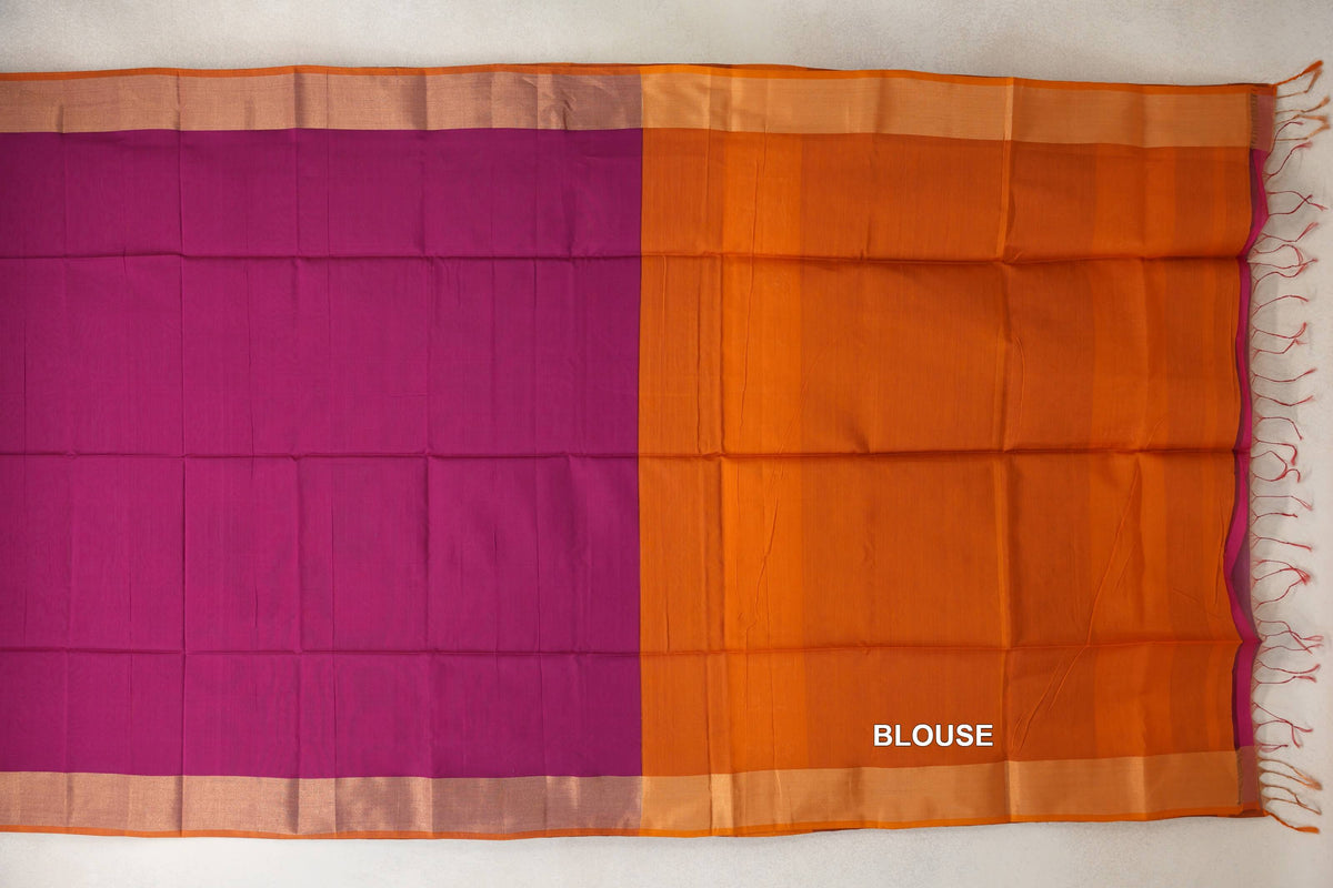 Maheshwari silk cotton saree laid flat, with a deep magenta body, orange selvedge and deep orange blouse piece with tassels at the end.