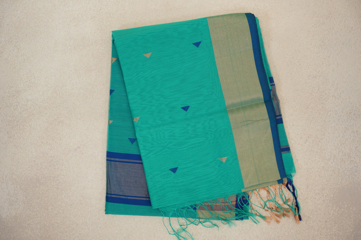 Folded sea green Maheshwari silk cotton saree with small blue and gold triangles, a broad gold-toned border, Classic Blue selvedge and tassels.