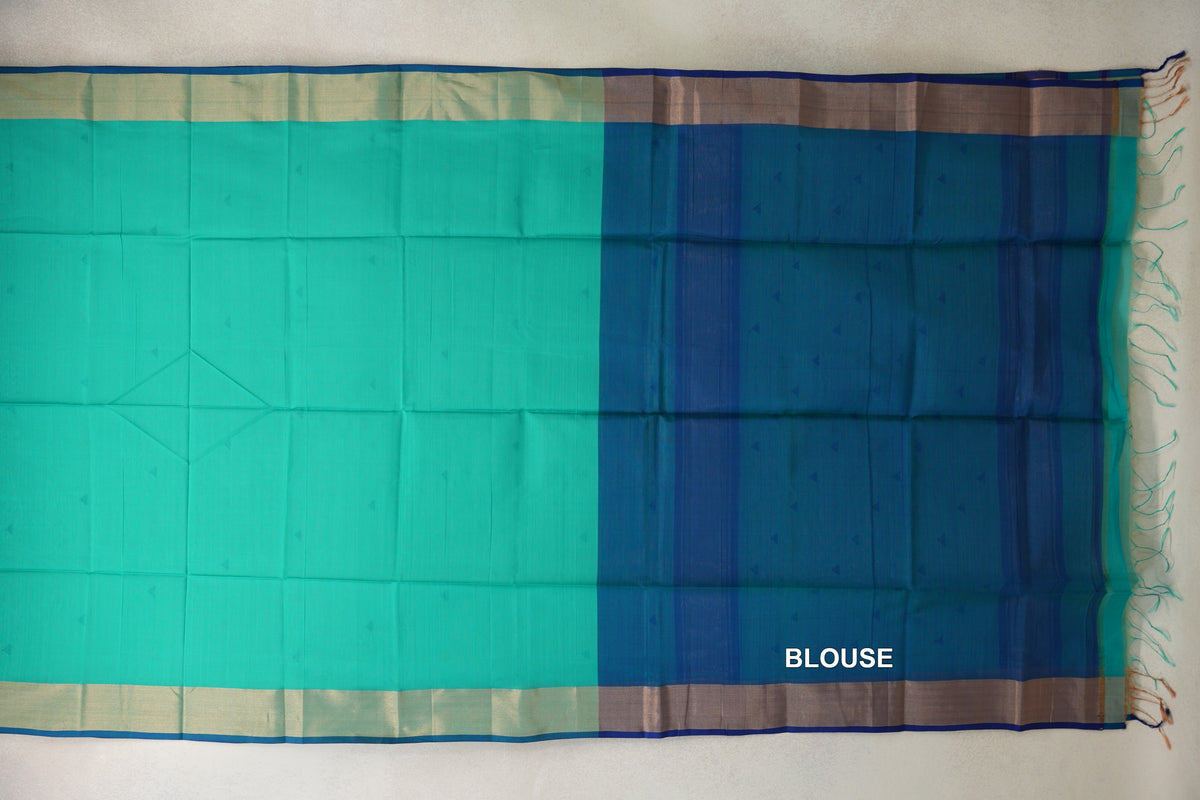 Maheshwari silk cotton saree spread flat, showing a sea green body beside a Classic Blue blouse piece, light borders with blue edging and tassels.