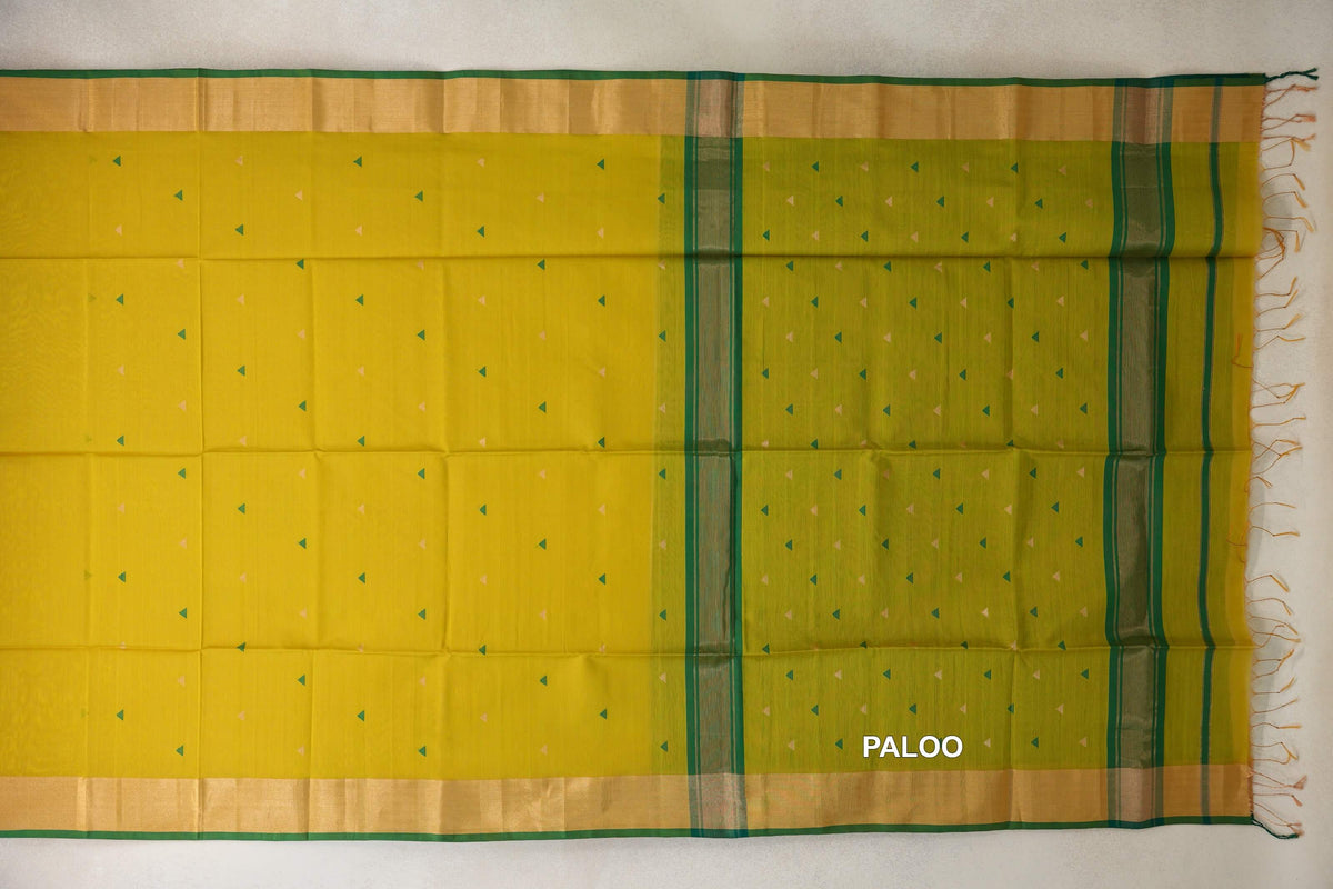 Maheshwari silk cotton saree laid flat, with a bright lemon yellow body, green-toned pallu, tiny triangle motifs, gold-toned borders and end tassels.