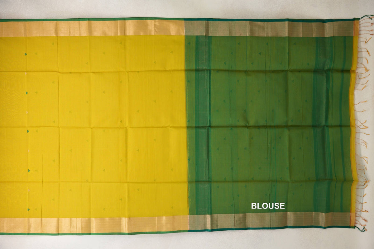 Maheshwari silk cotton saree laid flat, with a bright lemon yellow body, small triangular motifs, green-edged borders and a leaf green blouse piece on the right.