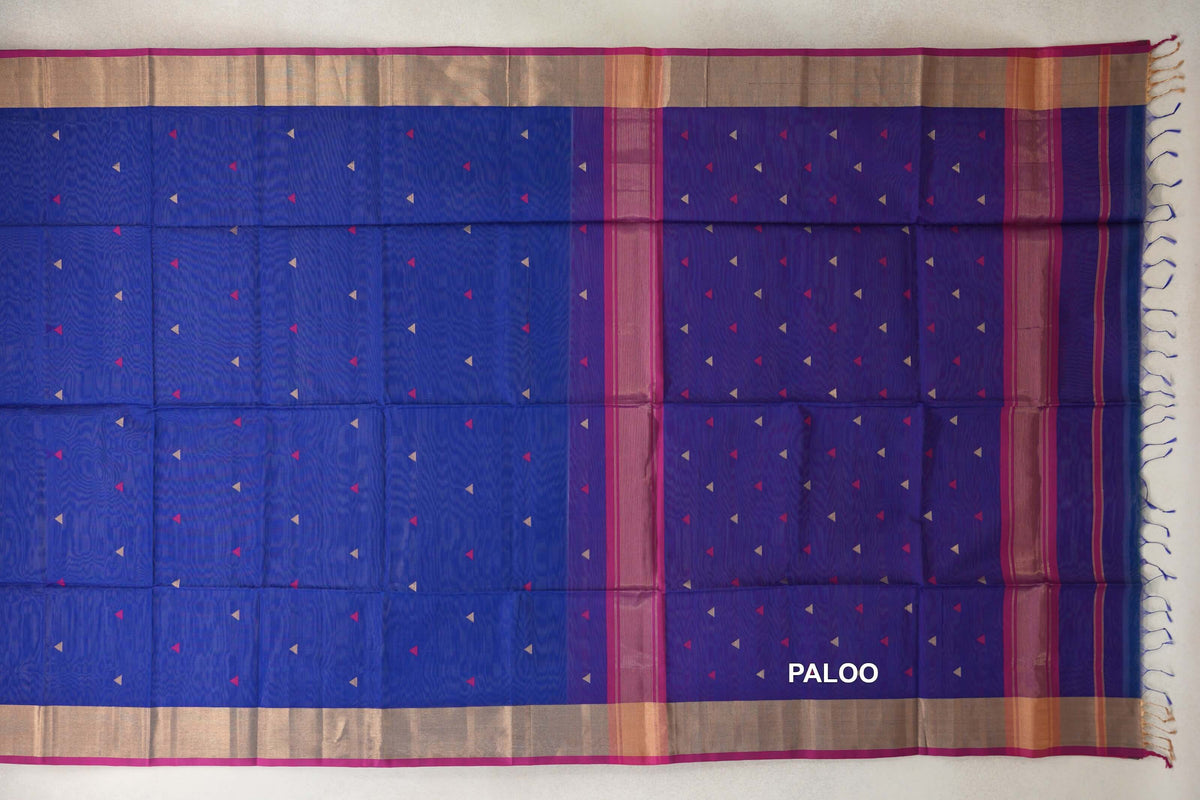 Bright royal blue Maheshwari silk cotton saree laid open, with small pink and beige triangles, a striped blue pallu, beige borders, pink edging and tassels.