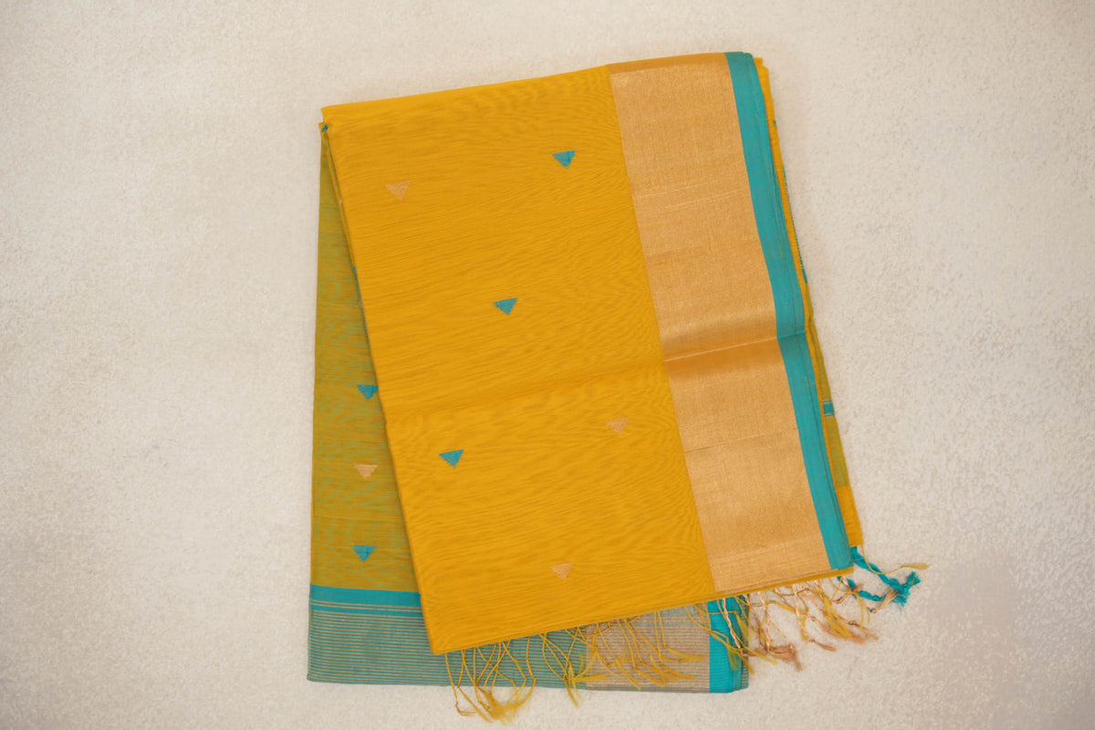 Folded mustard yellow Maheshwari silk cotton saree with small turquoise and beige triangles, a broad border, turquoise blue edge and tassels.