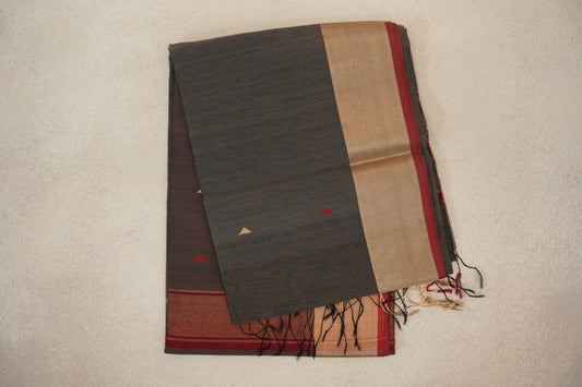 Folded charcoal grey Maheshwari silk cotton saree with small triangle accents, a broad gold-toned border edged in deep red, and tassels.