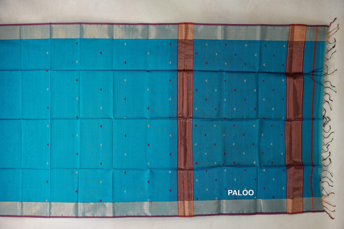 Spread-out pallu of a bright turquoise blue Maheshwari silk cotton saree with small red and pale triangles, deep red bands and tassels.