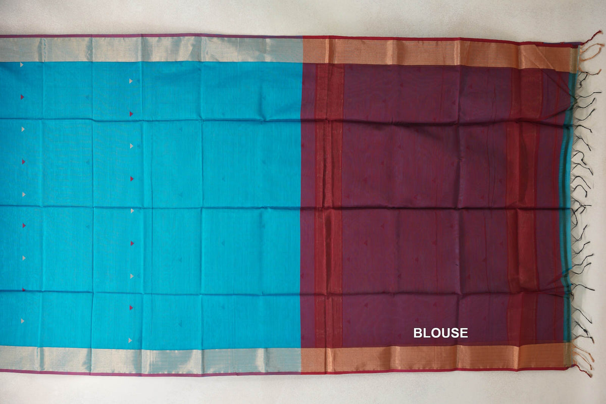Maheshwari silk cotton saree laid flat, with a bright turquoise blue body, small triangle accents, pale borders and a deep red blouse piece with tassels.