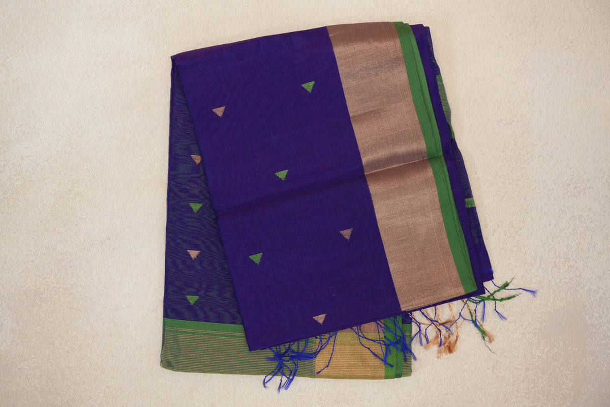Folded deep violet Maheshwari silk cotton saree with small green and gold triangles, a broad gold-toned border, green selvedge and tassels.