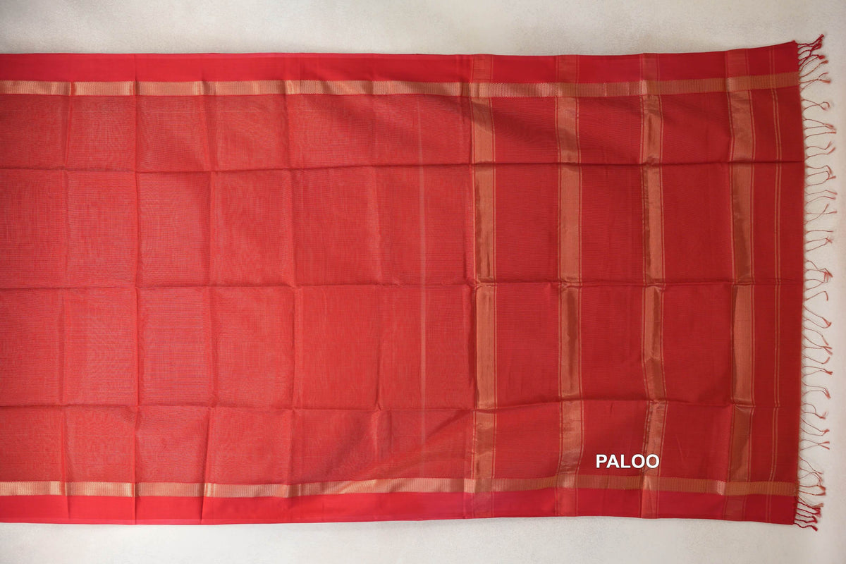 Red Maheshwari silk cotton saree laid flat, showing a plain body, gold-toned borders and a striped pallu with tassels.