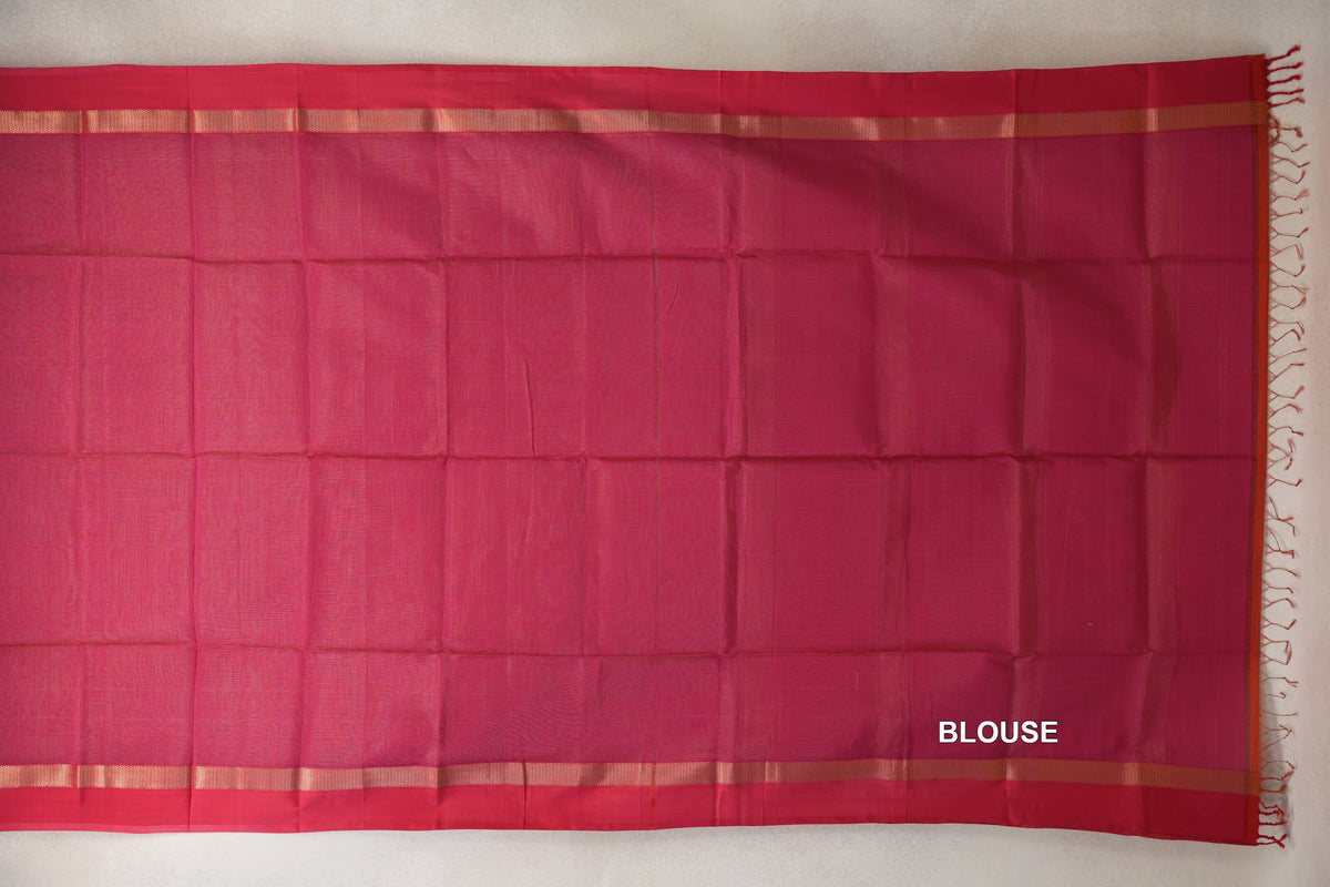 Rani pink Maheshwari silk cotton blouse piece laid flat, with deep pink edges, narrow gold-toned stripes and tassels at one end.